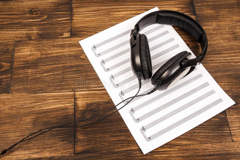Grandi cuffie professionali nere che si trovano sullo strato di musica sui precedenti di legno fotografie stock libere da diritti Grandi cuffie professionali nere che si trovano sullo strato di musica sui precedenti di legno fotografie stock libere da diritti