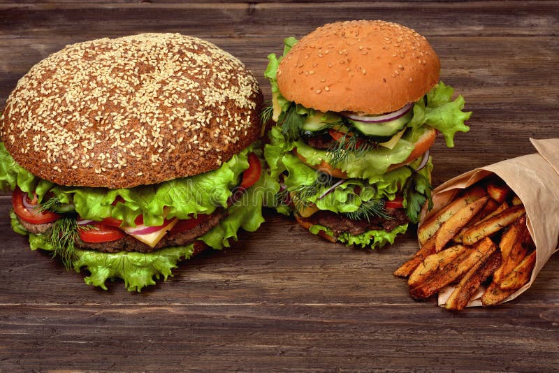 Grandi hamburger con le patate fritte per uno spuntino rapido immagine stock Grandi hamburger con le patate fritte per uno spuntino rapido immagine stock
