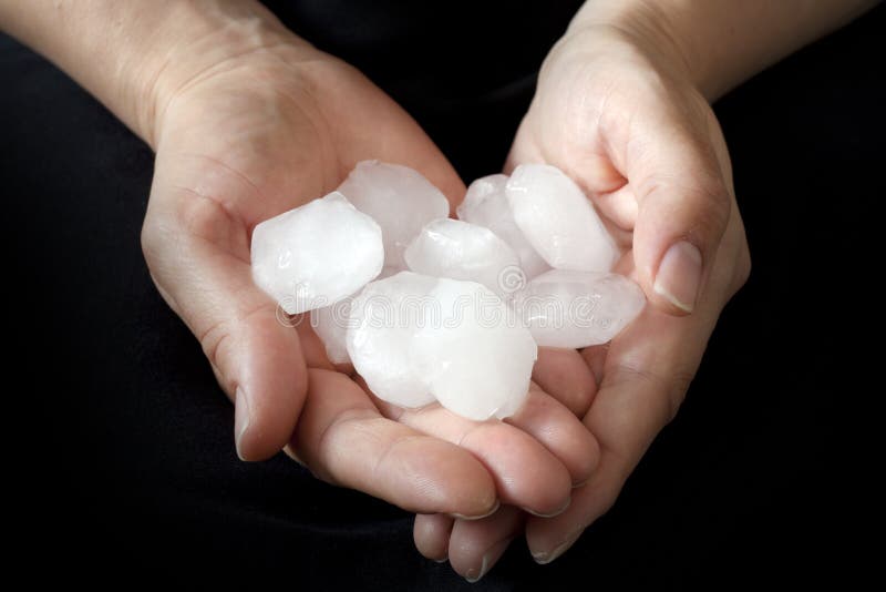 Weather anomaly hail in hands against black background. Weather anomaly hail in hands against black background