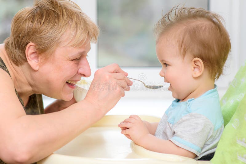 Grandmother gives baby food from a spoon