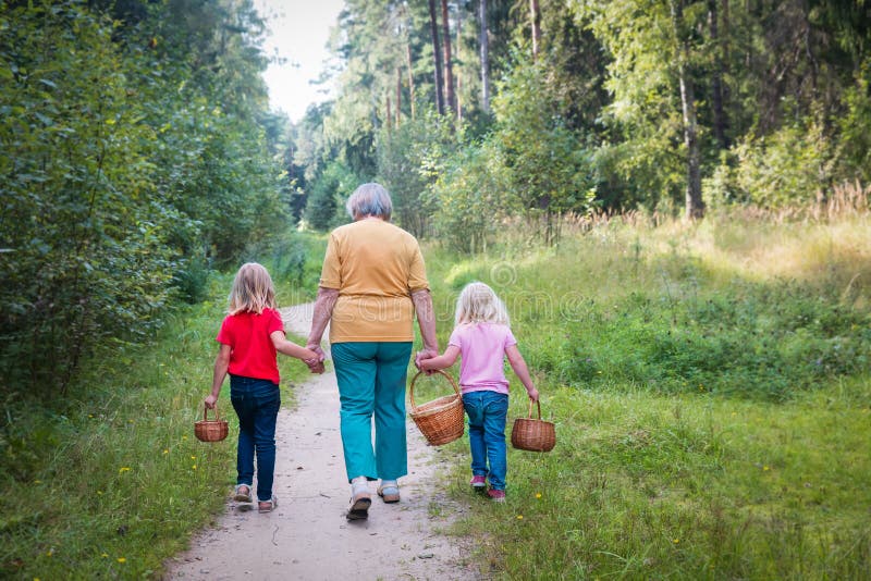 Grandmother with kids with baskets going to forest