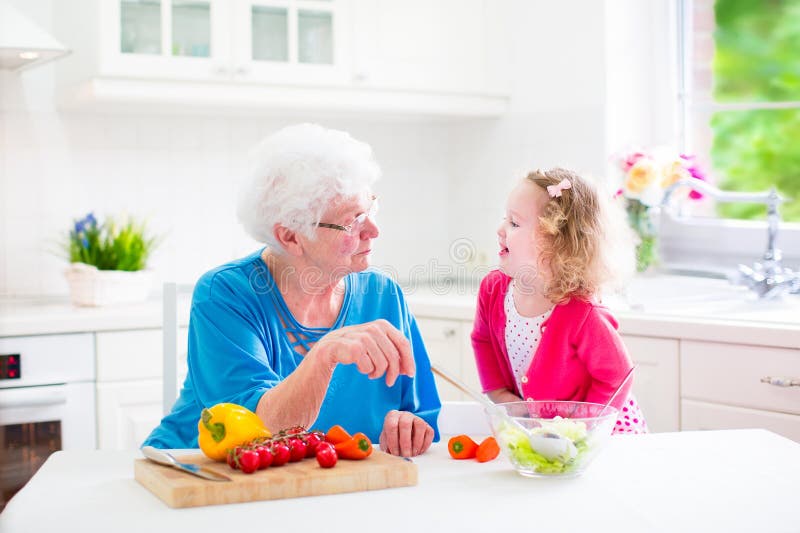 Grandmother and little girl making salad stock photos Grandmother and little girl making salad stock photos