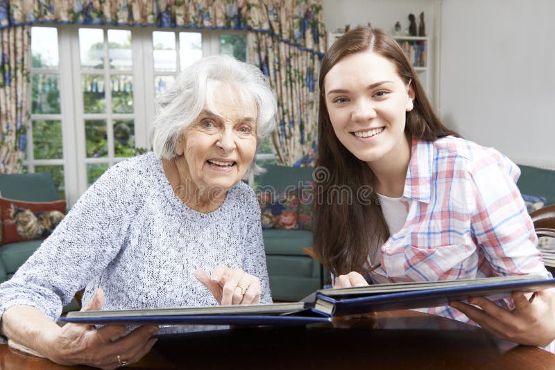Grandmother Looking At Photo Album With Teenage Granddaughter royalty free stock photography Grandmother Looking At Photo Album With Teenage Granddaughter royalty free stock photography