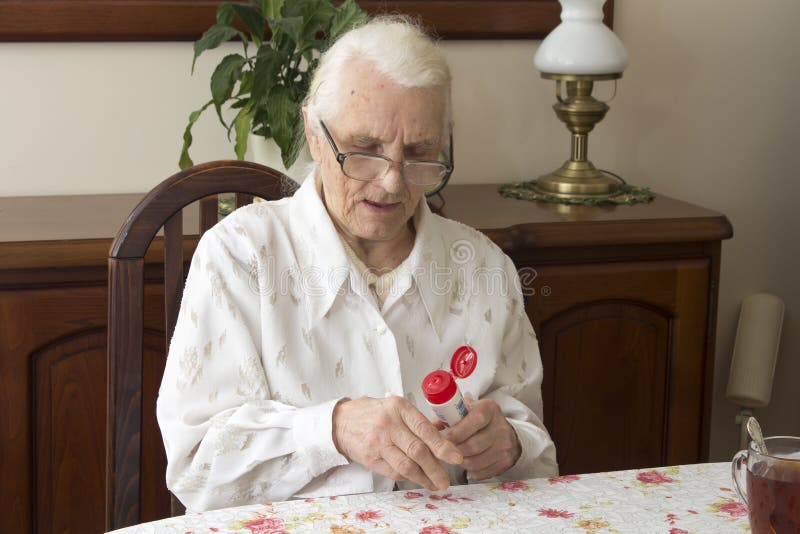 Grandmother sitting at a table in the living room and lubricates hand salve. stock photography Grandmother sitting at a table in the living room and lubricates hand salve. stock photography
