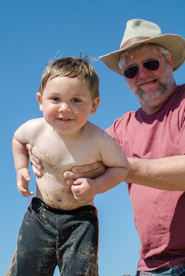 Abuelo arriba húmedo, arenoso un nino sobre el Playa.