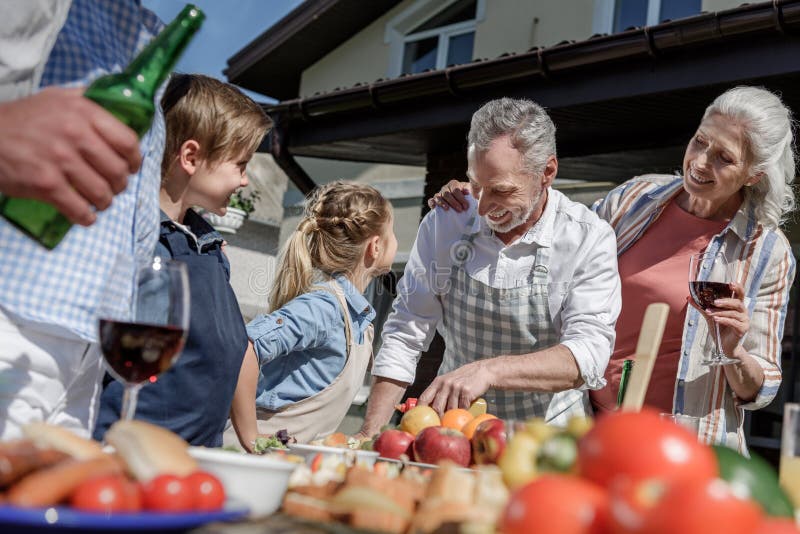 Grandparents and grandchildren preparing food on picnic outdoors stock photography Grandparents and grandchildren preparing food on picnic outdoors stock photography