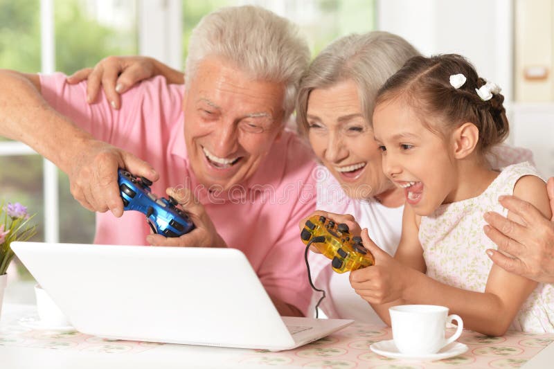 Grandparents and granddaughter playing computer game