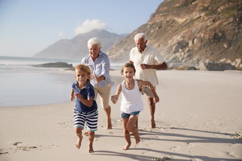 Grandparents Running Along Beach With Grandchildren On Summer Vacation stock photography Grandparents Running Along Beach With Grandchildren On Summer Vacation stock photography