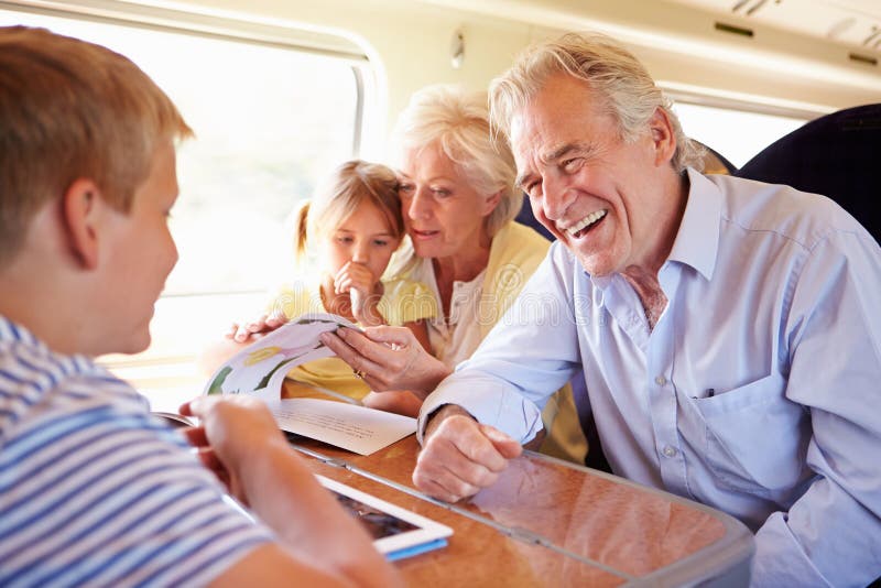 Grands-parents et petits-enfants détendant sur le voyage en train images stock Grands-parents et petits-enfants détendant sur le voyage en train images stock