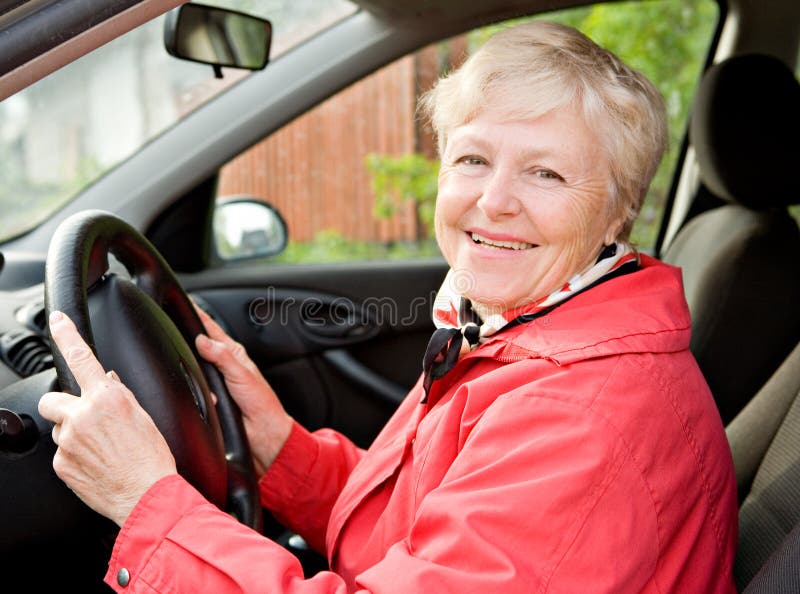 The smiling elderly woman in a red jacket at the wheel the car. Old granny stock images, royalty-free photos and pictures