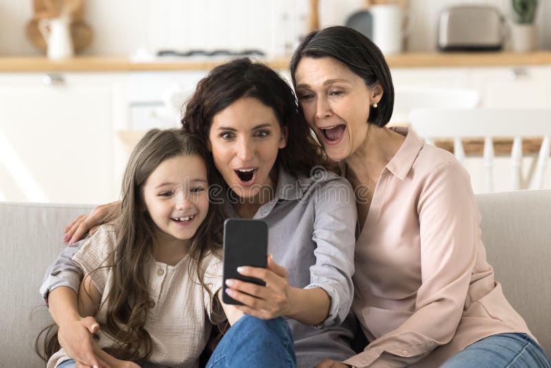 Granny Mama kleines Mädchen schrie aufgeregt und schaute ans Telefon lizenzfreie stockbilder