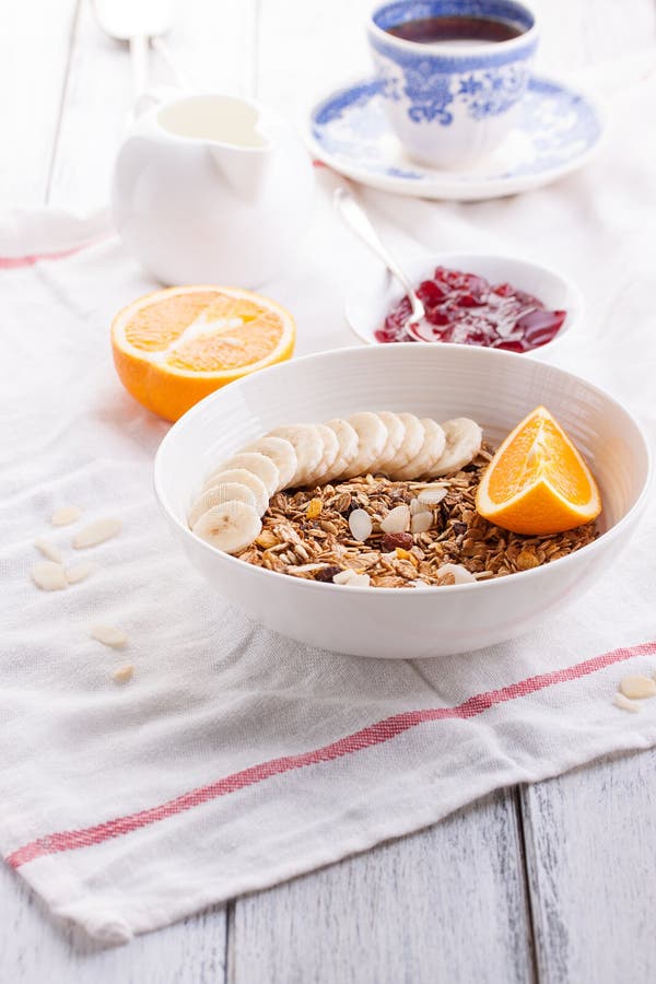 Granola caseiro com frutos frescos em uma bacia branca com doce, leite e café em um fundo de madeira para o café da manhã imagens de stock royalty free Granola caseiro com frutos frescos em uma bacia branca com doce, leite e café em um fundo de madeira para o café da manhã imagens de stock royalty free