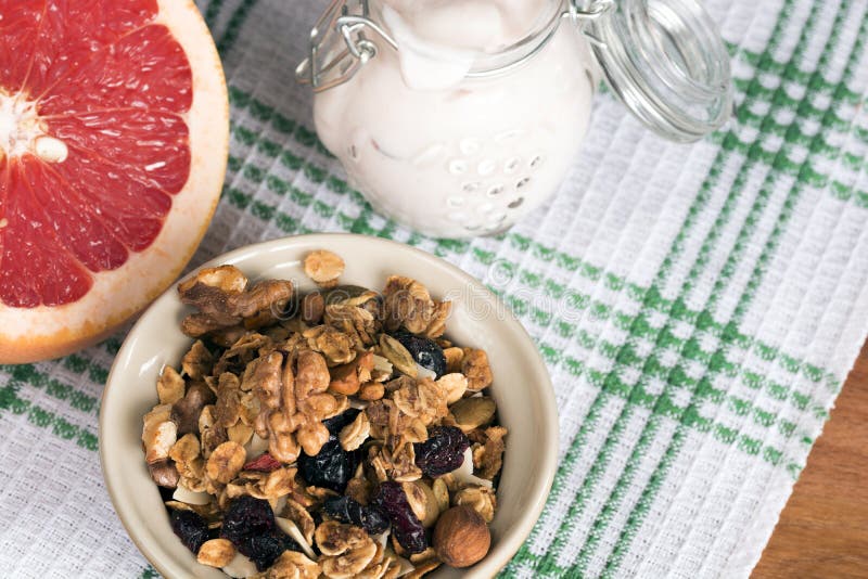 Granola de diversos tipos de cereais com porcas, aparas do coco e os arandos secados Frasco com iogurte caseiro e toranja imagem de stock Granola de diversos tipos de cereais com porcas, aparas do coco e os arandos secados Frasco com iogurte caseiro e toranja imagem de stock