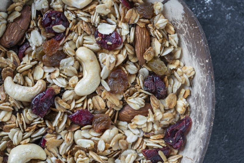 Granola with oatmeal, dried fruit, honey, raisins, dry cranberry, almond and cashew nuts in a coconut bowl, close up