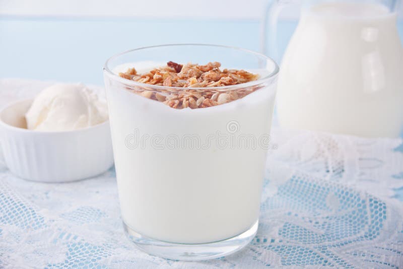Granola with Yogurt in Glass, Milk and Cream Cheese on a Blue Table