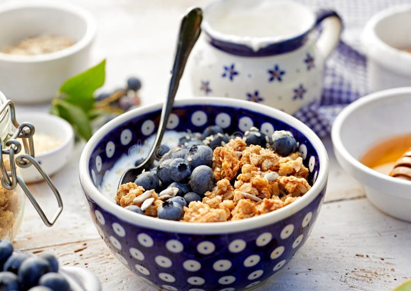 Granola με το φυσικό γιαούρτι, τα φρέσκα βακκίνια, τα καρύδια και το μέλι σε ένα κεραμικό κύπελλο σε έναν άσπρο ξύλινο πίνακα Εύγ στοκ εικόνα Granola με το φυσικό γιαούρτι, τα φρέσκα βακκίνια, τα καρύδια και το μέλι σε ένα κεραμικό κύπελλο σε έναν άσπρο ξύλινο πίνακα Εύγ στοκ εικόνα
