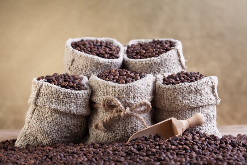 Granos de café asados en pequeños bolsos de arpillera fotografía de archivo
