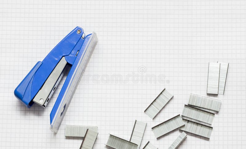 Grapadora y pilas azules de oficina Staples en el trozo de papel, Clos fotos de archivo libres de regalías Grapadora y pilas azules de oficina Staples en el trozo de papel, Clos fotos de archivo libres de regalías