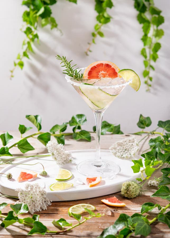 Grapefruit and cucumber, rosemary and lime cocktail, refreshing, cold drinks with ice on a rustic table. Summer garden party