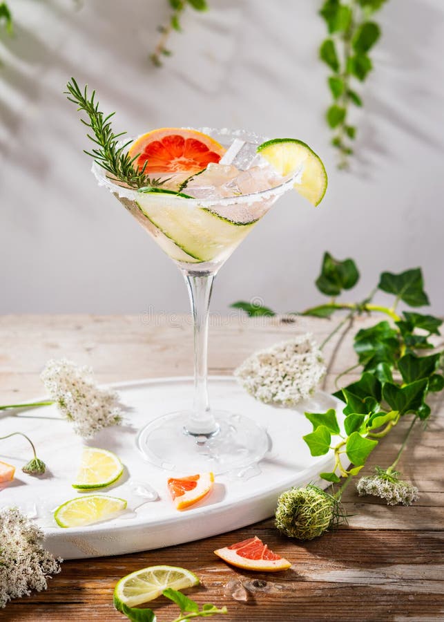 Grapefruit and cucumber, rosemary and lime cocktail, refreshing, cold drinks with ice on a rustic table. Summer garden party