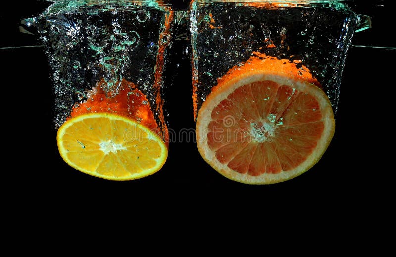 Grapefruit and orange falling into water