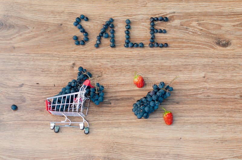 Grapes inside small shopping cart, word sale and percent sign