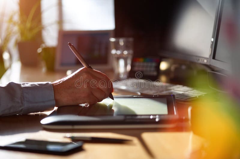 Graphic Designer working with digital Drawing tablet and Pen on a computer. Smooth tracking shot with nice backlit lensflare.