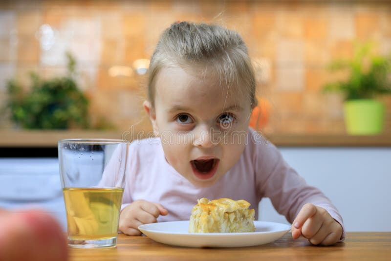 Grappig meisje die appeltaart thuis eten stock afbeelding Grappig meisje die appeltaart thuis eten stock afbeelding