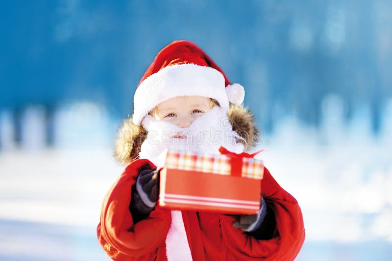 Grappig weinig jongen die Santa Claus-kostuum in de winter sneeuwpark dragen stock foto's Grappig weinig jongen die Santa Claus-kostuum in de winter sneeuwpark dragen stock foto's