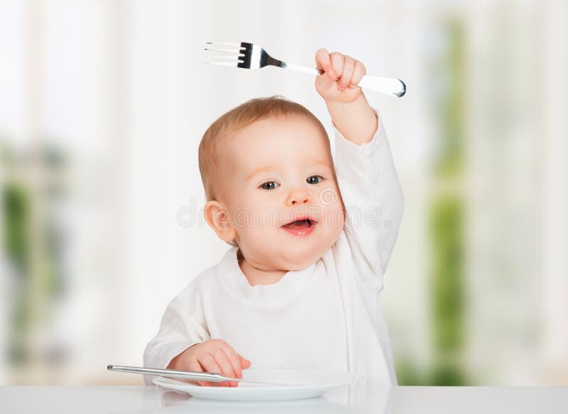 Grappige baby met een mes en een vork die voedsel eten royalty-vrije stock foto's Grappige baby met een mes en een vork die voedsel eten royalty-vrije stock foto's