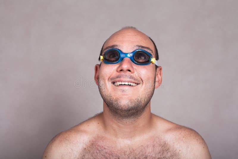 Grappige mens in zwemmende en beschermende brillen die omhoog dagdromen eruit zien