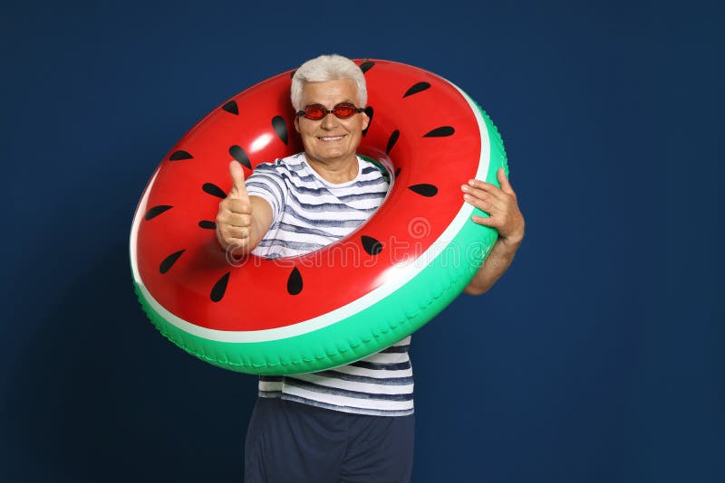 Grappige rijpe mens met heldere opblaasbare ring op blauwe achtergrond stock foto's Grappige rijpe mens met heldere opblaasbare ring op blauwe achtergrond stock foto's