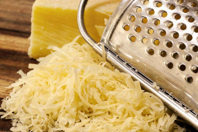 Grated Cheese and Grater on Board royalty free stock image.