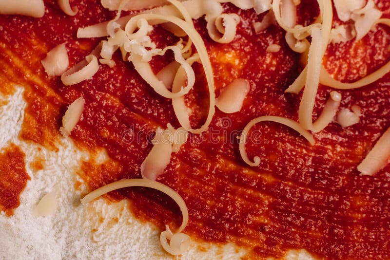 Grated Cheese for Pizza Close Up on Ketchup Coated Dough Stock Photo