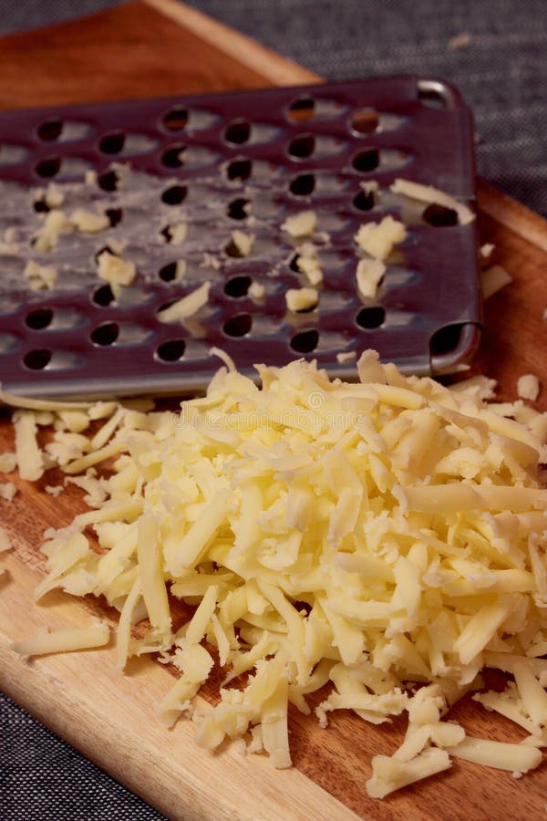 Grated mogen cheddarost med ett rivjärn arkivfoton Grated mogen cheddarost med ett rivjärn arkivfoton