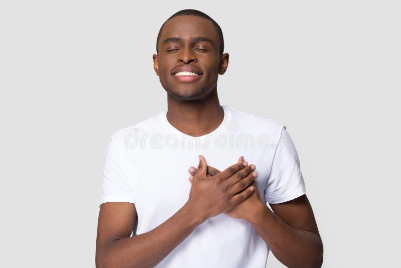 Grateful happy pleased african man holding hands on chest to heart feeling love appreciation gratitude honesty, thankful sincere proud black guy thanking isolated on white studio blank background. Grateful happy pleased african man holding hands on chest to heart feeling love appreciation gratitude honesty, thankful sincere proud black guy thanking isolated on white studio blank background