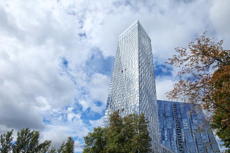 Gratte-ciel avec Windows reflété contre un ciel bleu avec de grands nuages et arbres moscou 07 09 2016 images libres de droits Gratte-ciel avec Windows reflété contre un ciel bleu avec de grands nuages et arbres moscou 07 09 2016 images libres de droits