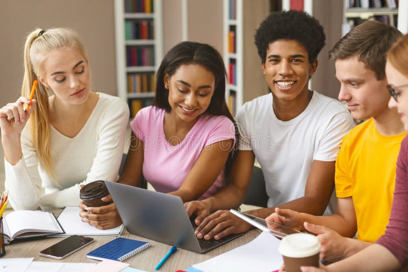 Grattis till unga studenter som arbetar med projekt i biblioteket royaltyfri bild Grattis till unga studenter som arbetar med projekt i biblioteket royaltyfri bild