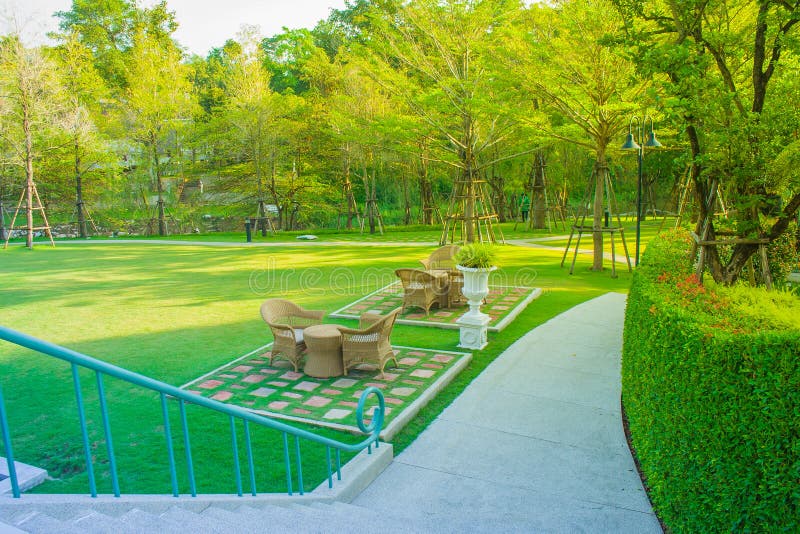 Graue Webartstühle gelegen auf grünem Gras im Park mit Morgensonnenlicht im Hintergrund lizenzfreie stockfotografie Graue Webartstühle gelegen auf grünem Gras im Park mit Morgensonnenlicht im Hintergrund lizenzfreie stockfotografie