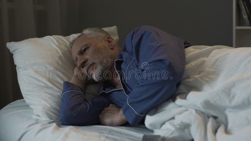 Grauer behaarter Mann, der im Bett liegt und unter Schlaflosigkeit, Krise und Gesundheit leidet stockfotos Grauer behaarter Mann, der im Bett liegt und unter Schlaflosigkeit, Krise und Gesundheit leidet stockfotos