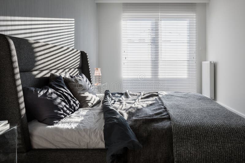 Sunny, gray bedroom with double bed and window with long blinds. Sunny, gray bedroom with double bed and window with long blinds