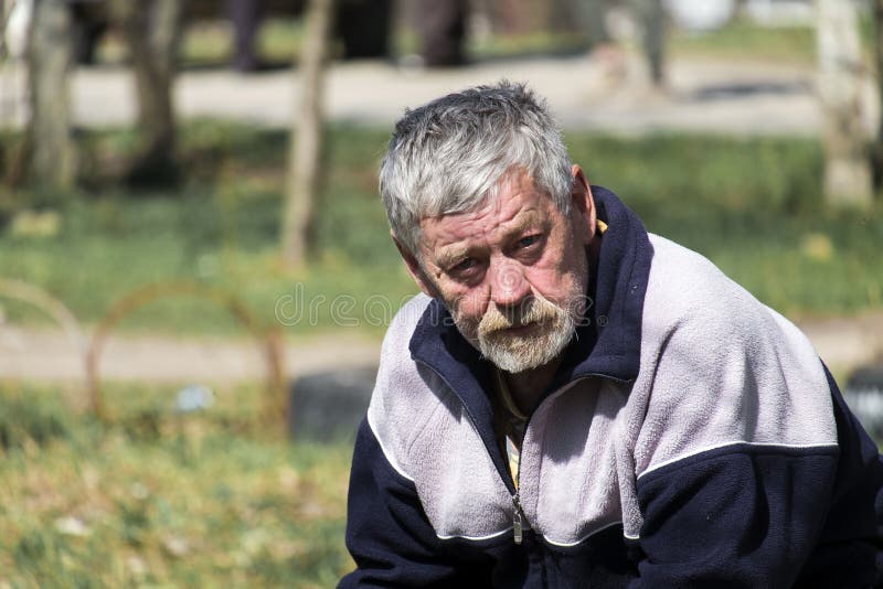 Grauhaariger bärtiger alter Mann, der auf einer Bank und Blicken sitzt lizenzfreies stockfoto Grauhaariger bärtiger alter Mann, der auf einer Bank und Blicken sitzt lizenzfreies stockfoto