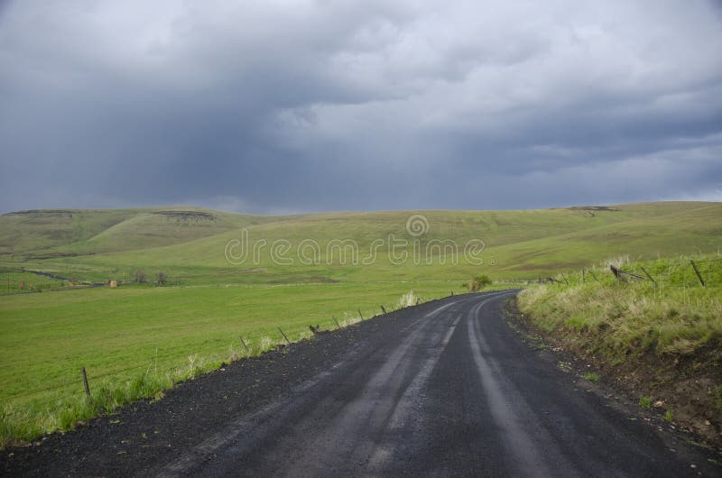 Gravel rural road beneath stormy sky