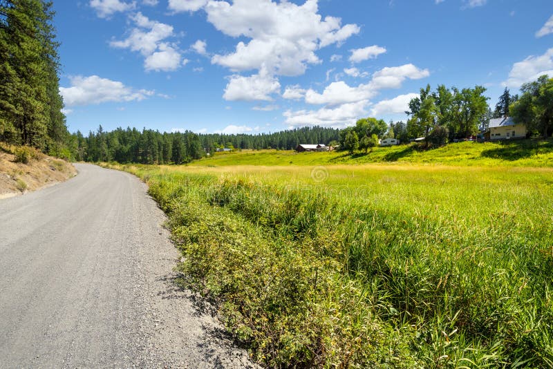 A gravel rural road with homes and ranches above a meadow in the rural Spokane area of Washington, USA royalty free stock image A gravel rural road with homes and ranches above a meadow in the rural Spokane area of Washington, USA royalty free stock image