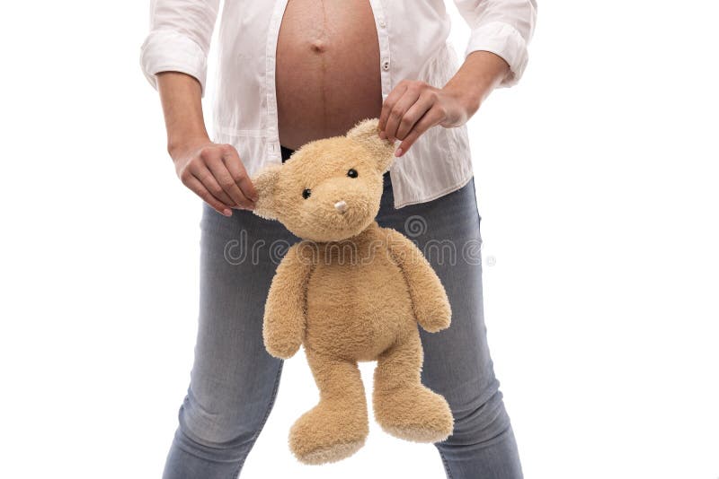 Gravid flicka som rymmer en nallebjörn vid öronen på vit bakgrund royaltyfri bild Gravid flicka som rymmer en nallebjörn vid öronen på vit bakgrund royaltyfri bild