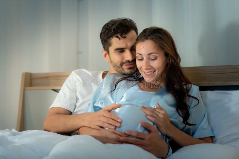 Gravid kvinna med man i sovrummet med en atmosfär av roligt att prata royaltyfri foto