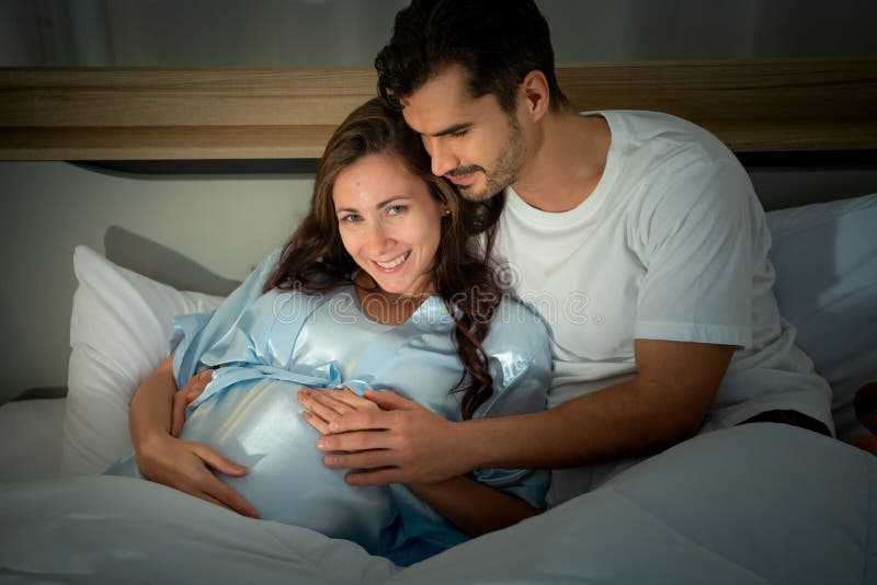 Gravid kvinna med man i sovrummet med en atmosfär av roligt att prata arkivbild