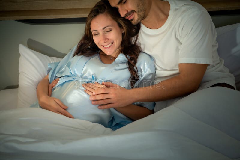 Gravid kvinna med man i sovrummet med en atmosfär av roligt att prata arkivbild