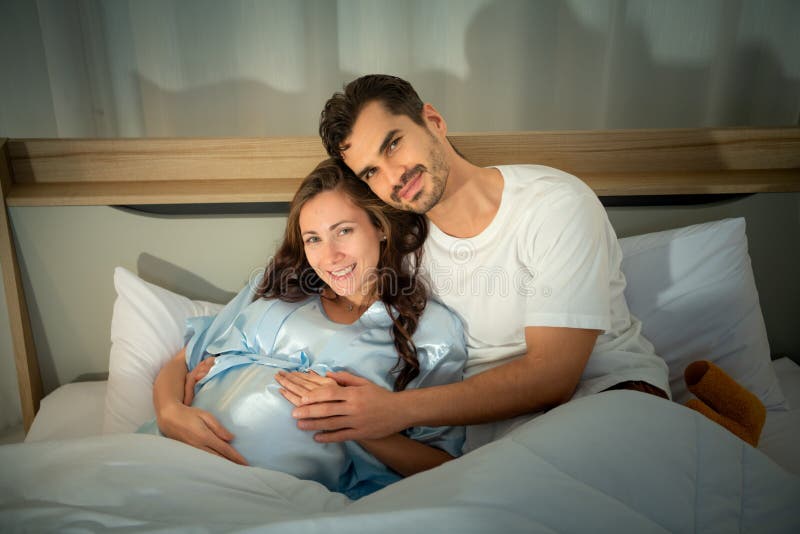 Gravid kvinna med man i sovrummet med en atmosfär av roligt att prata arkivfoton