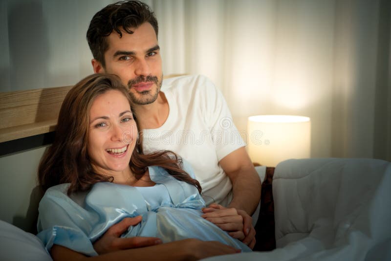 Gravid kvinna med man i sovrummet med en atmosfär av roligt att prata arkivbilder
